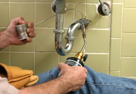 Showing a plumbing contractor working on repairing a sink pipe